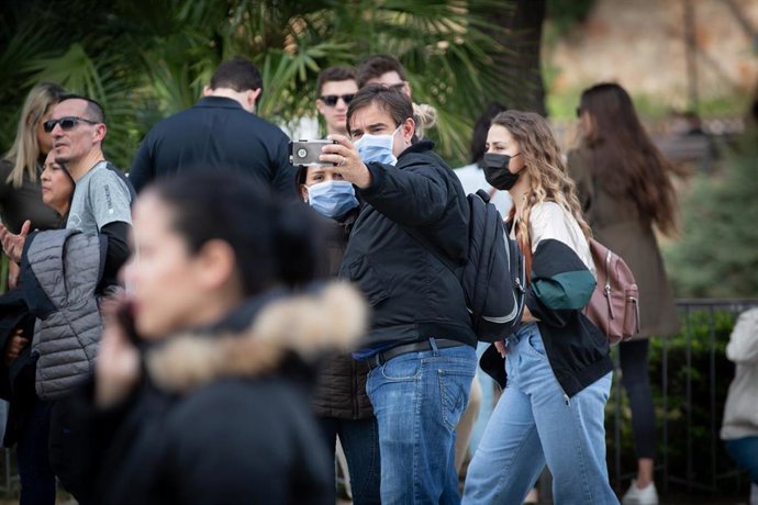 Dos personas se hacen un selfie y otra camina en una zona cercana a la Sagrada Familia, protegidas las tres con mascarillas ante el avance del coronavirus en Barcelona