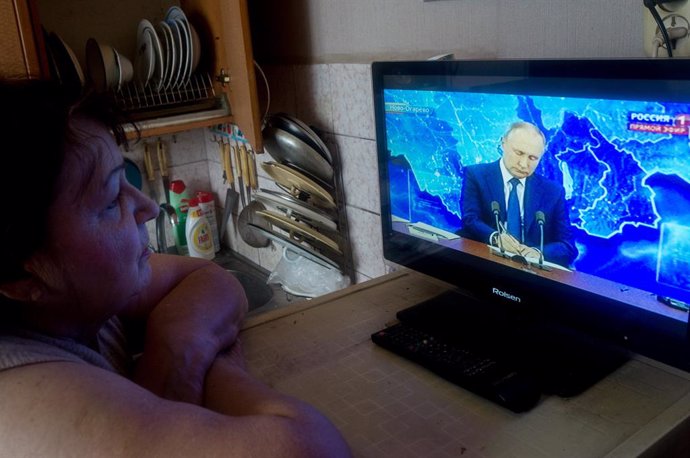Una mujer observa una intervención del presidente ruso, Vladimir Putin, por televisión.