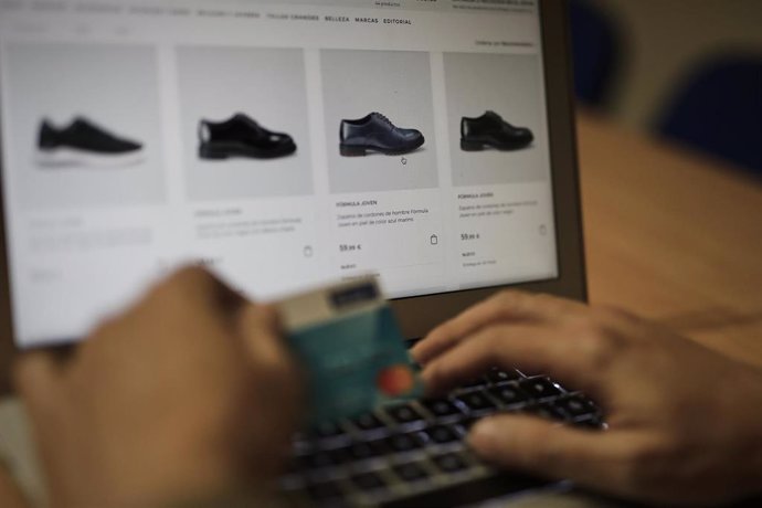 Una persona se dispone a pagar con su tarjeta de crédito una compra online realizada con su ordenador en la página de un comercio