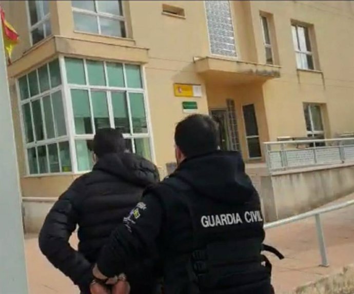 Un guardia civil escoltando al joven detenido por una treintena de casos de delitos sexuales en Mallorca.