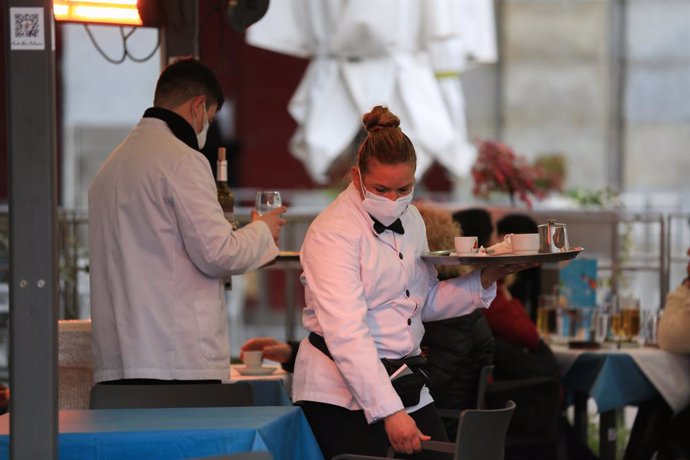 Dos camareros trabajan en la terraza de un bar en el centro de Madrid (España), a 5 de febrero de 2021. La Comunidad de Madrid amplía desde este viernes el número de personas que pueden compartir mesa en las terrazas, que pasa de cuatro a un máximo de s