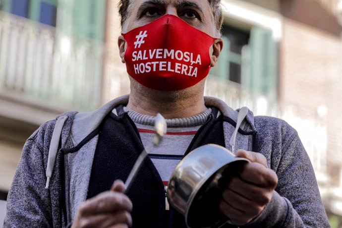 Un hombre con una mascarilla en la que se lee: `Salvemos la hostelería durante la cacerolada promovida por La Coordinadora Empresarial del Ocio y la Hostelería contra el cierre de la hostelería en la Comunidad Valenciana, en Valencia (España), a 21 de en