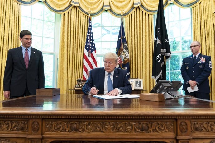HANDOUT - 15 May 2020, US, Washington: US President Donald Trump (C), joined by US Department of DefenCe Secretary Mark Esper (L) and US Space Force Senior Enlisted Advisor CMSgt Roger Towberman, signs an Armed Forces Day Proclamation at the Oval Office