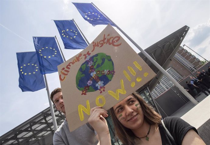 24 May 2019, Frankfurt am Main: A woman holds a sign with the inscription "Climate Justice Now" in front of the European Central Bank (ECB) during the Fridays for Future - climate strikes for the implementation of the Paris World Climate Agreement.