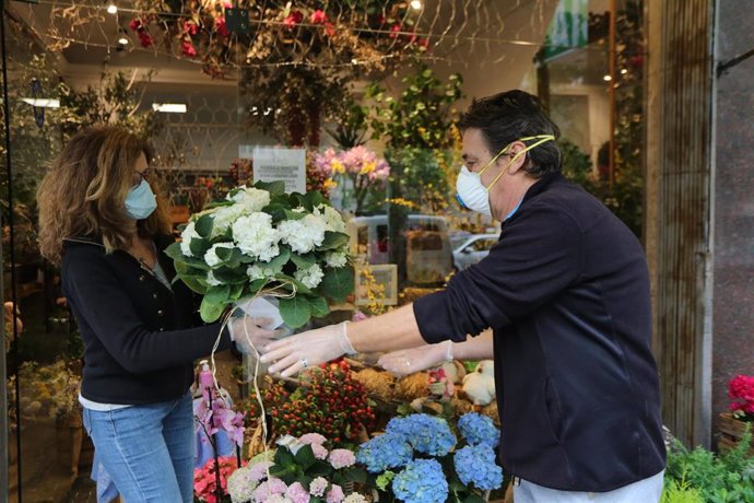 Alicia Casla, propietaria de la Floristería Caslaflor (calle de los Hermanos Pinzón, 3), entrega un ramo de flores a un repartidor que las lleva a domicilio