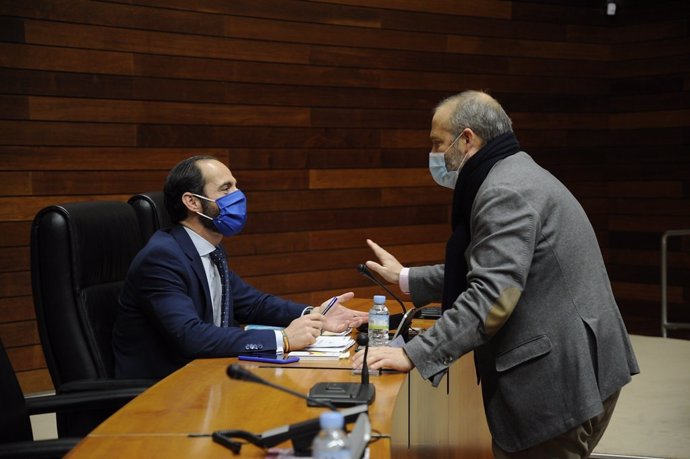 El consejero de Economía, Rafael España, hablando con un diputado autonómico en la Asamblea