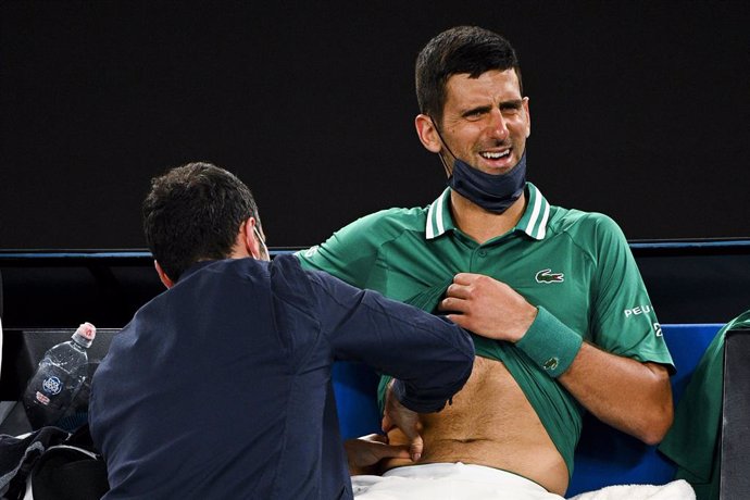 12 February 2021, Australia, Melbourne: Serbian tennis player Novak Djokovic receives medical attention while on a break from action against USA's Taylor Fritz during their men's singles third Round match of the Australian Open Grand Slam tennis tournam