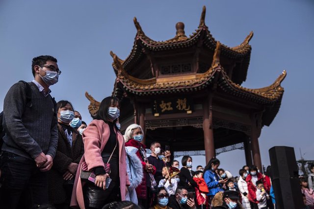 Un grupo de personas con mascarilla ve uno de los espectáculos callejeros del primer día del nuevo año lunar en Wuhan (China).