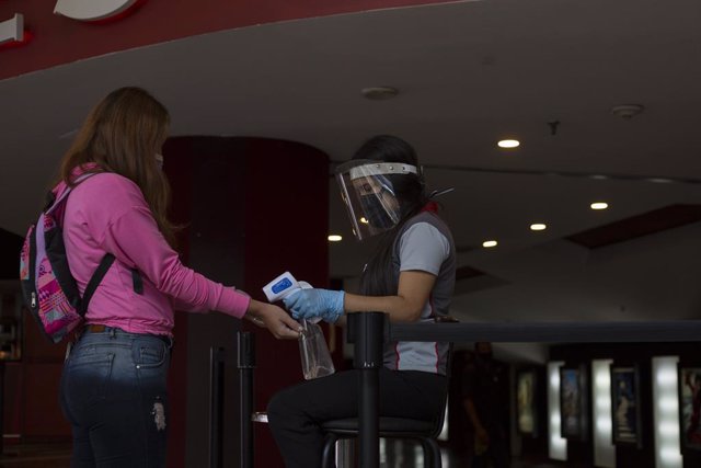 27 January 2021, Venezuela, Caracas: An employee checks the temperature of a visitor in a cinema. Cinemas and theatres are allowed to reopen in Venezuela. Photo: Pedro Rances Mattey/dpa