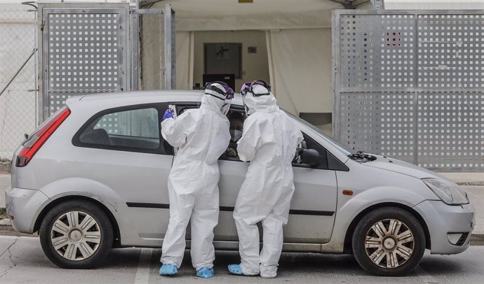 Dos sanitarios realizan una prueba PCR a una persona desde su vehículo