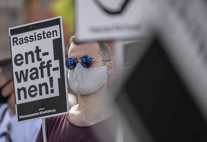 22 August 2020, Hessen, Hanau: A man holds a sign says "Disarm racists" during a rally at the official commemoration of the racist attacks in Hanau at the square in the city centre. Photo: Boris Roessler/dpa