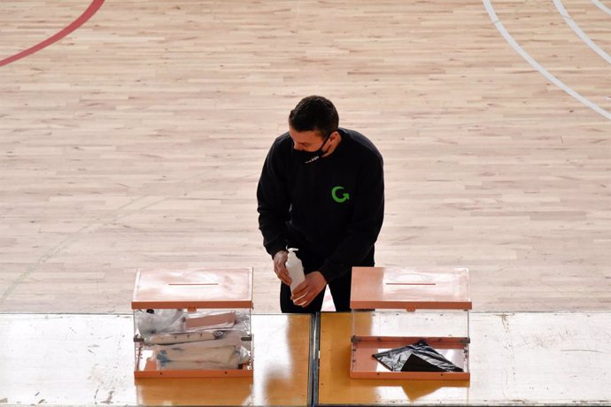 Un treballador al costat de dues urnes en el dispositiu electoral per a les eleccions catalanes d'aquest diumenge