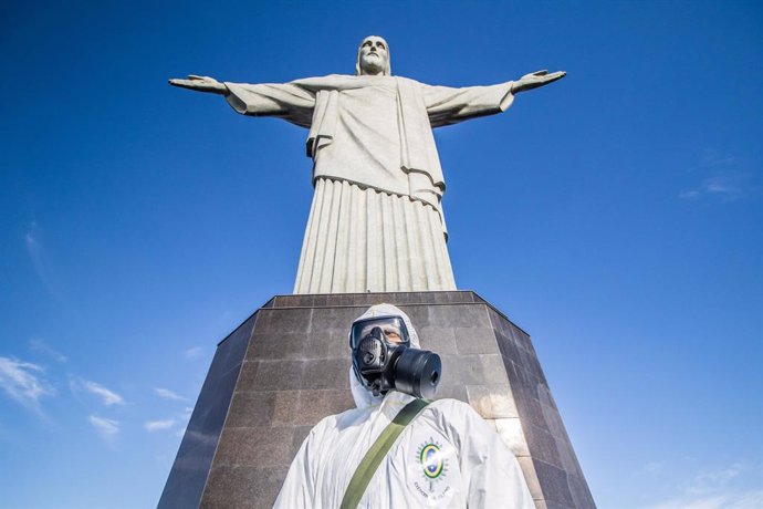 13 August 2020, Brazil, Rio de Janeiro: A military member wears a coverall suit and a face mask stands in front of the statue of Christ the Redeemer, during a disinfection process for the main tourist spot in Rio de Janeiro which will be reopened next w