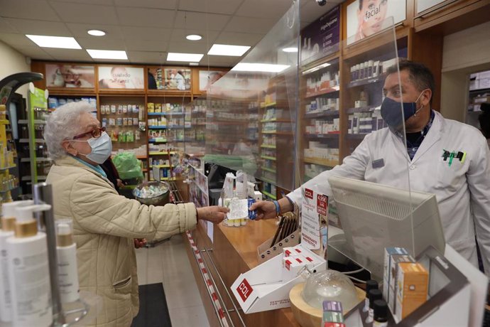 Una anciana recoge una mascarilla FFP2 en la farmacia situada en la C/Tucán (Carabanchel), en Madrid (España), a 4 de febrero de 2021