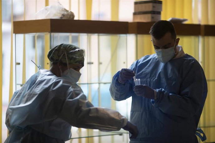 Un trabajador sanitario sostiene una probeta en un dispositivo de cribado masivo de antígenos.