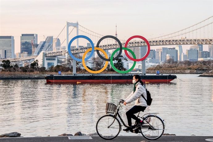 Una mujer con mascarilla pasa por delante de los aros olímpicos de Tokio, en Japón