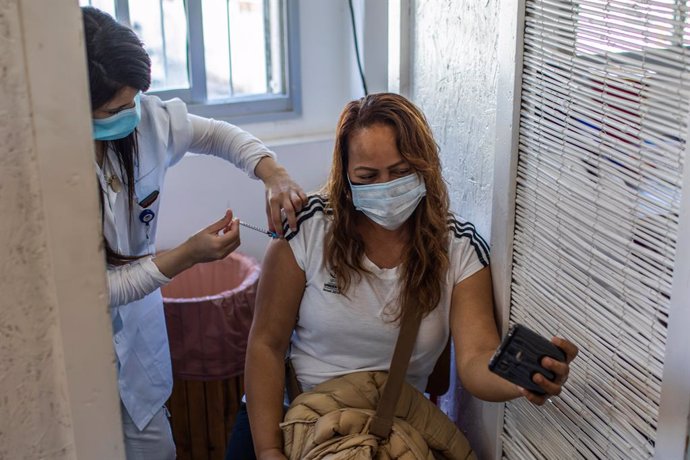 09 February 2021, Israel, Tel Aviv: A woman receives her dose of the COVID-19 vaccine during a campaign to vaccinate foreign workers and refugees against coronavirus at the vaccination centre of the Tel Aviv Sourasky Medical Centre. Photo: Ilia Yefimovi