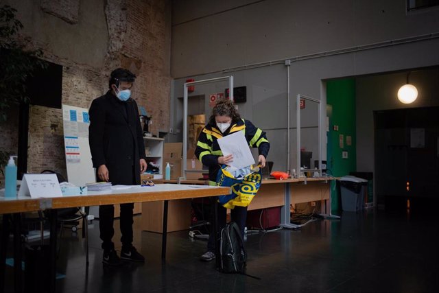 Una trabajadora de Correos deja los votos por correo en una mesa electoral de Antic Convent St. Agustí en Barcelona este 14F.