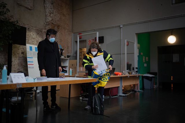 Una treballadora de Correus deixa els vots per correu en una mesa electoral de l'Antic Convent St. Agustí a Barcelona aquest 14F.