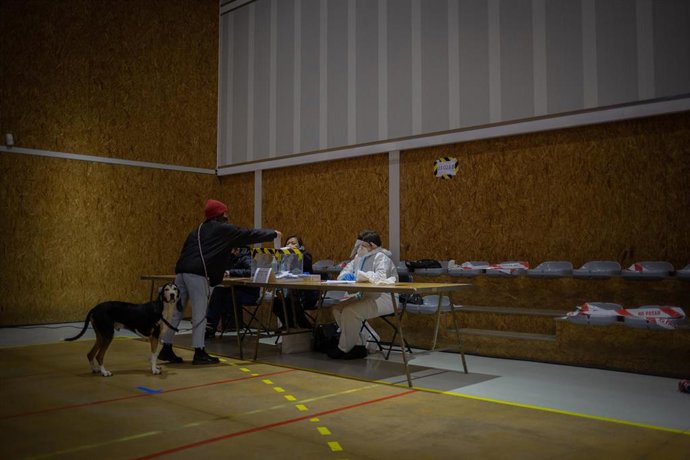 Un hombre vota con su perro en el Polideportivo Tres Xemeneies, en Barcelona, Cataluña (España), a 14 de febrero de 2021