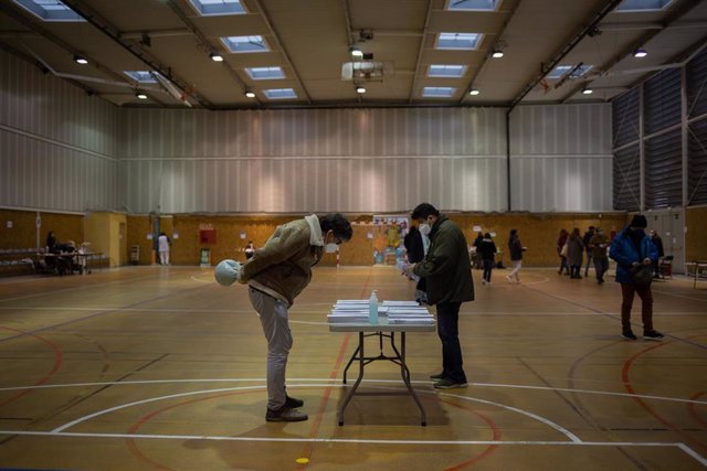 Un hombre elige su papeleta electoral en el Polideportivo Tres Xemeneies, en Barcelona, Cataluña (España), a 14 de febrero de 2021