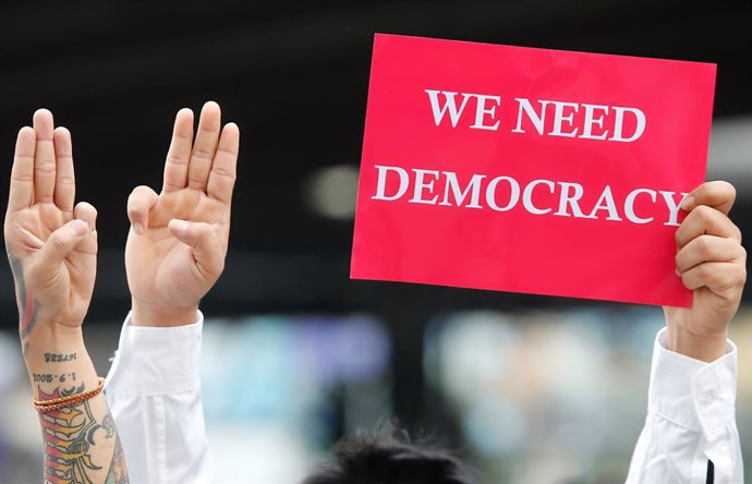 10 February 2021, Thailand, Bangkok: Demonstrators show the three-finger salute, as a sign of resistance and in support of the protests against the military coup in Myanmar  during a rally demanding the prime minister to resign and reforms in the monarc