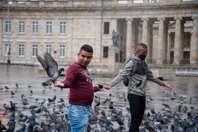Dos ciudadanos juegan con palomas en Plaza Bolívar, en Bogotá, la capital de Colombia, durante la pandemia de COVID-19. 