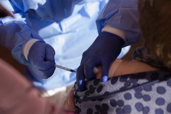 Una mujer mayor de 90 años recibe la vacuna de Pfizer contra la Covid-19, en una carpa habilitada en la explanada del centro de salud del municipio Lora del Río. En Sevilla (Andalucía, España), a 15 de febrero de 2021.