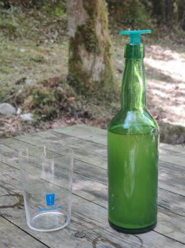 Botella de sidra asturiana y vaso de sidra en una terraza de Covadonga.