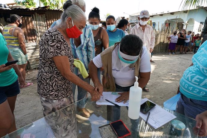 Un trabajador humanitario hondureño utiliza una huella dactilar para registrar a un residente de la comunidad Brisas de la Bueso cerca de Choloma, Honduras, para recibir suministros de socorro.