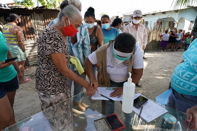 Un trabajador humanitario hondureño utiliza una huella dactilar para registrar a un residente de la comunidad Brisas de la Bueso cerca de Choloma, Honduras, para recibir suministros de socorro.