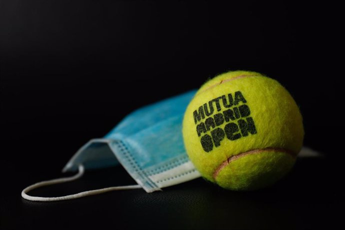 Una bola oficial del torneo de tenis profesional Mutua Madrid Open junto a una máscara quirúrgica,