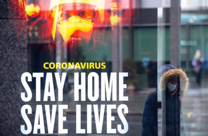 Una mujer pasa delante de un aviso del Gobiern británico en Londres durante la pandemia de COVID-19. 