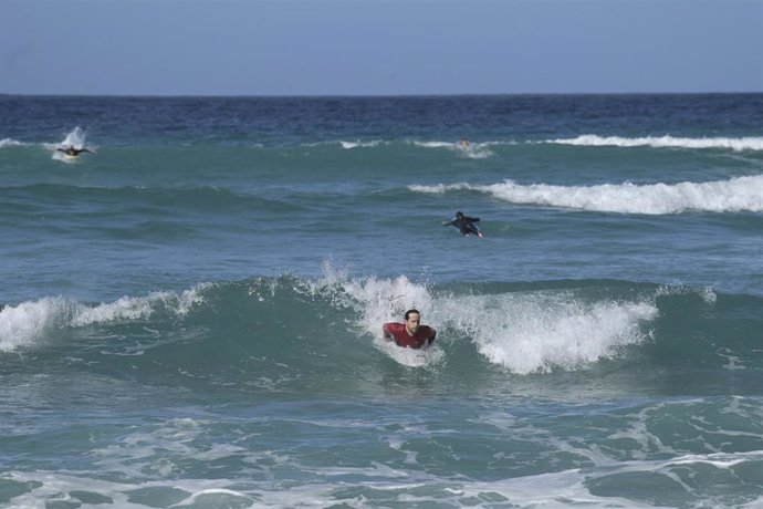 Surfistas disfrutan de un día de primavera anticipada con temperaturas de 20C de máxima y 11C de mínima en la playa del Orzán en A Coruña, Galicia (España), a 16 de febrero de 2021. Tras el paso de sucesivas borrascas que han dado lugar a temperaturas