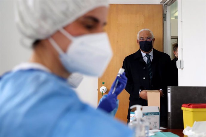 13 February 2021, Portugal, Lisbon: Portuguese Prime Minister Antonio Costa looks on as health technicians fill up syringes with a dose of the AstraZeneca Covid-19 vaccine on the first day of the security forces inoculation at the Conde de Lippe militar