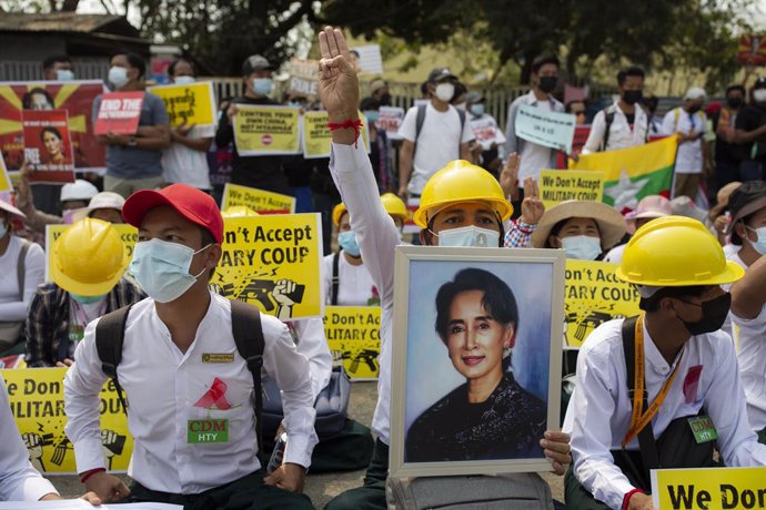 18 February 2021, Myanmar, Yangon: A protester holds a portrait of Aung San Suu Kyi and makes a three-finger salute during a protest against the military coup. Photo: Aung Kyaw Htet/SOPA Images via ZUMA Wire/dpa