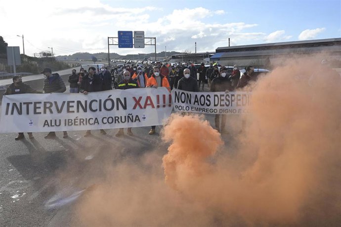 Concentración de los trabajadores de Alu Ibérica que sujetan dos pancartas en las que se lee: `Intervención Xa!, Non Aos Despedimentos delante de la fábrica en A Coruña