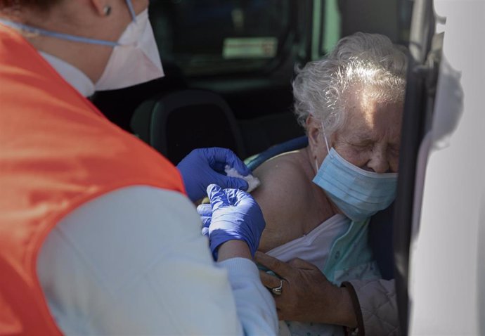 Una mujer mayor de 90 años recibe desde el coche la vacuna de Pfizer 