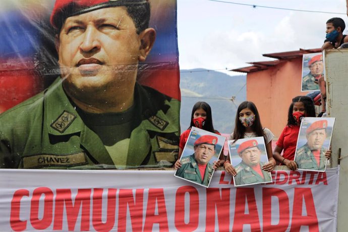 04 February 2021, Venezuela, Caracas: Children, along with a picture of the late President Hugo Chavez, take part in a march to commemorate the military uprising of 4 February 1992, in the 23 de Enero neighbourhood. Photo: Jesus Vargas/dpa