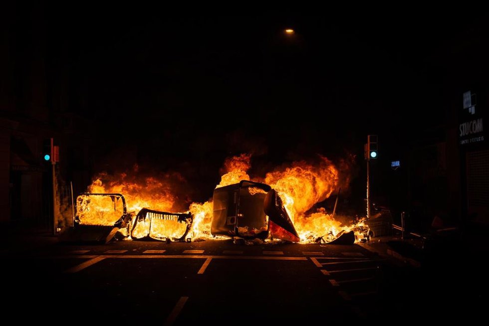 Un contenedor incendiado por los manifestantes que apoyan a Pablo Hasel durante los disturbios en Barcelona (España), a 17 de febrero de 2021. El rapero Pablo Hasel ingresó la mañana de ayer martes en el centro penitenciario de Ponent, en Lleida, tras s