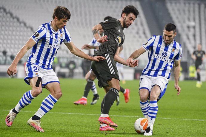18 February 2021, Italy, Turin: Manchester united's Bruno Fernandes (C) battles for the ball with Real Sociedad's Robin Le Normand and Joseba Zaldua during the UEFA Europa League round of 32 first leg soccer match between Real Sociedad and Manchester Un
