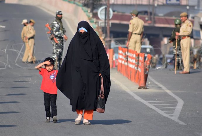Archivo - Una mujer con su hijo cerca de un puesto de control militar en la Cachemira india