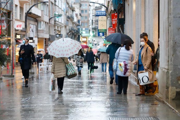 Varias personas pasean en una calle comercial en una jornada marcada por el inicio de la entrada en vigor de una desescalada gradual en la región, en Vigo, Galicia (España), a 17 de febrero de 2021. Galicia reabre hoy cines, teatros, auditorios, bibliot