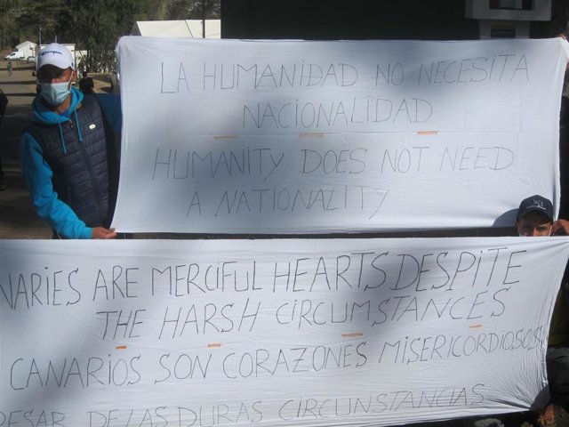 Migrantes magrebíes con pancartas en el campamento de Las Raíces