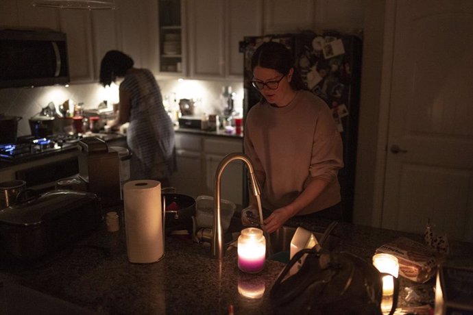 15 February 2021, US, Argyle: Women work in a kitchen lit by candles as millions in Texas are without power after a winter storm slammed the state. Photo: Chris Rusanowsky/ZUMA Wire/dpa