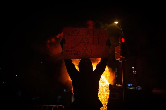 Uno de los manifestantes que apoyan a Pablo Hasel con una pancarta durante los disturbios en Barcelona el 17 de febrero