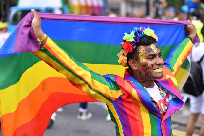 Archivo - 06 July 2019, England, London: A reveller holds a rainbow flag ahead of the 2019 Pride Parade. Photo: Dominic Lipinski/PA Wire/dpa