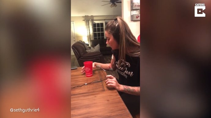 Esta mujer trata de beber de un vaso con una unidad TENS colocada que emite pequeñas descargas