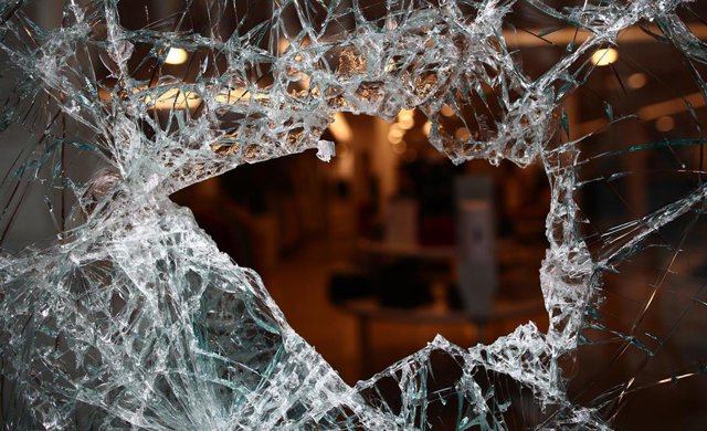 Vista de una tienda a través de su cristalera rota tras una noche de protestas