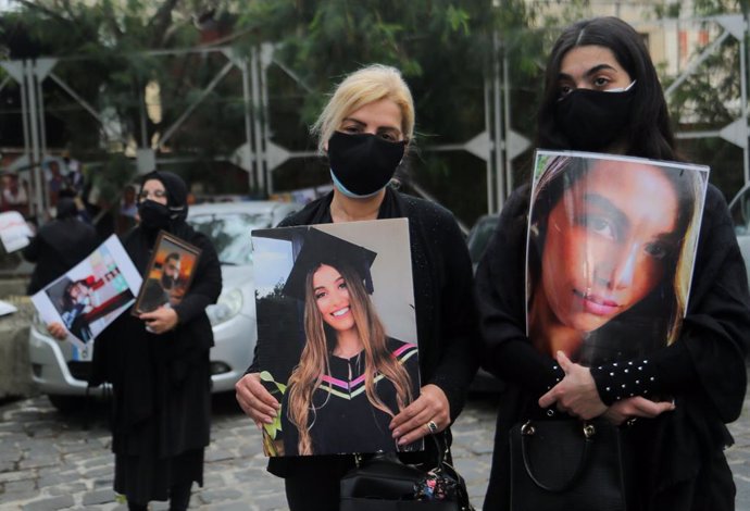 04 February 2021, Lebanon, Beirut: Families of those who were killed in 4th of August Beirut port blast carry pictures of their beloved ones as they attend a silent sit-in at the entrance of the port to mark six months after of the blast that killed mor